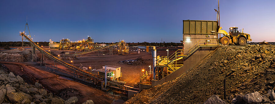 Bulldozer loading rocks into the crusher within the copper mine head at dusk in NSW Australia